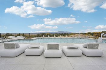 A pool surrounded by white lounge chairs.